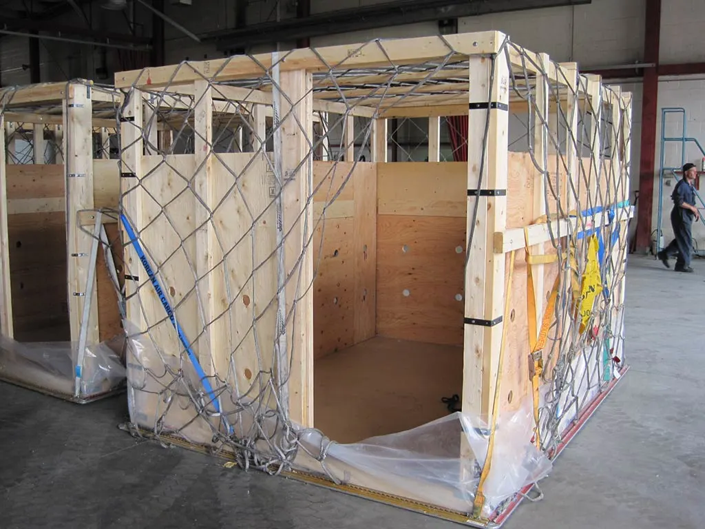 Custom wooden shipping crate with ventilation holes and cargo netting, manufactured by 204 Pallet & Packaging for secure transport of oversized freight.