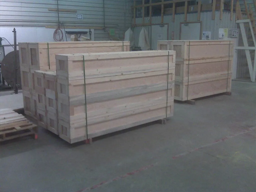 Long custom wood crates are stacked in a warehouse. Available at 204 Pallet & Packaging in Winnipeg, Manitoba.